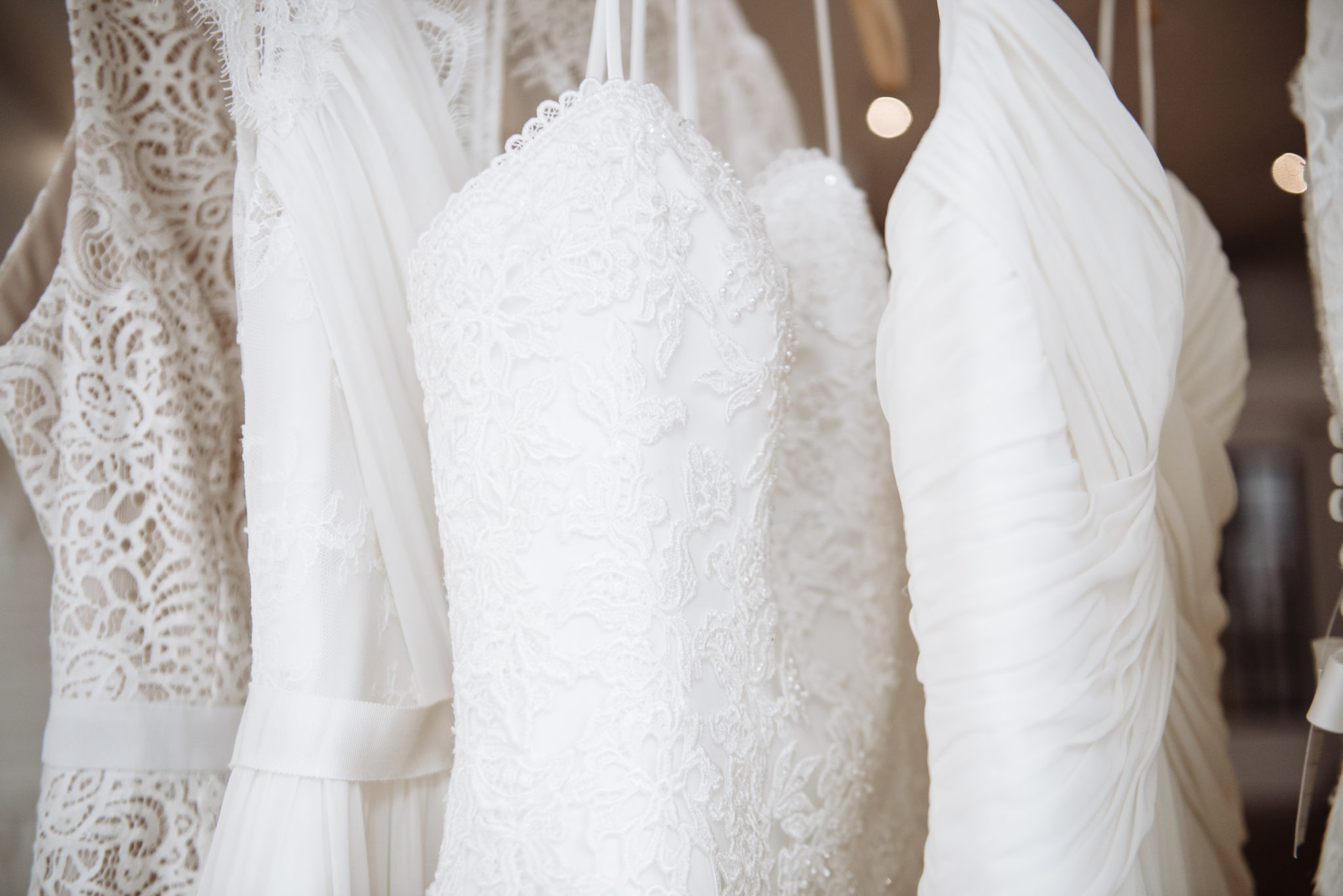 Four wedding dresses made from different fabrics hanging on a rack