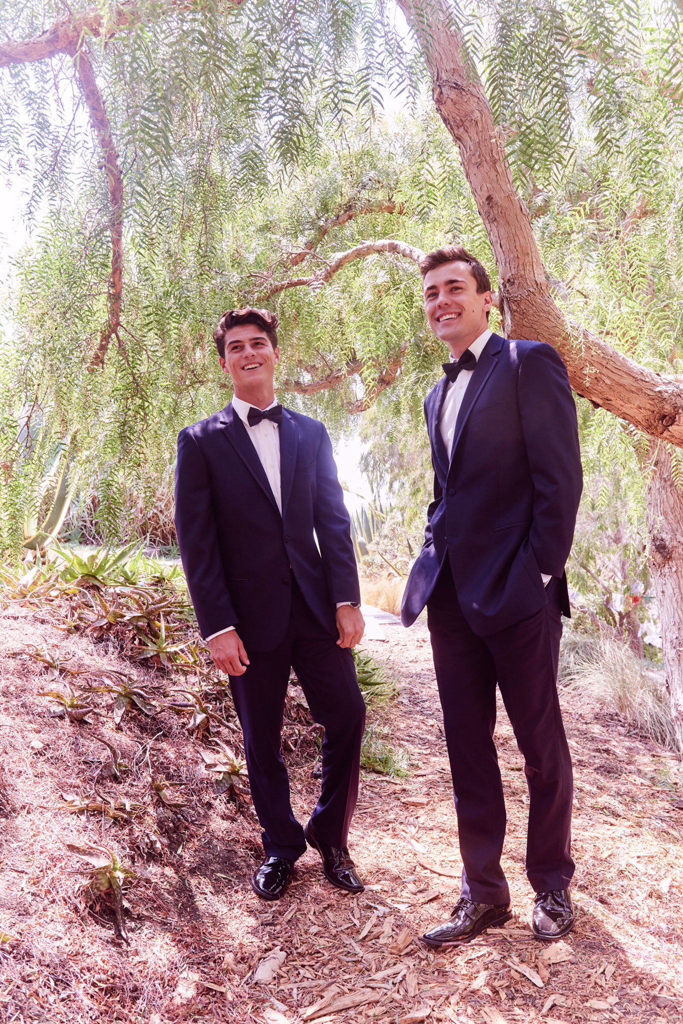 Two groomsmen in tuxedos in an outdoor setting
