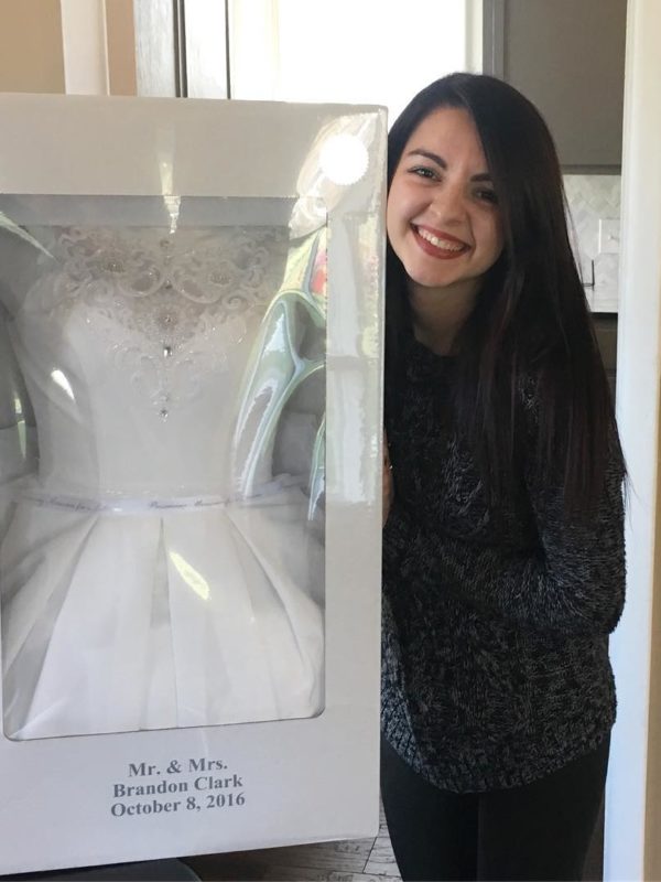 Woman smiling holding wedding dress preservation kit box