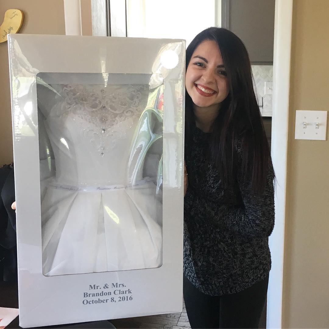 Woman smiling holding wedding dress preservation kit box