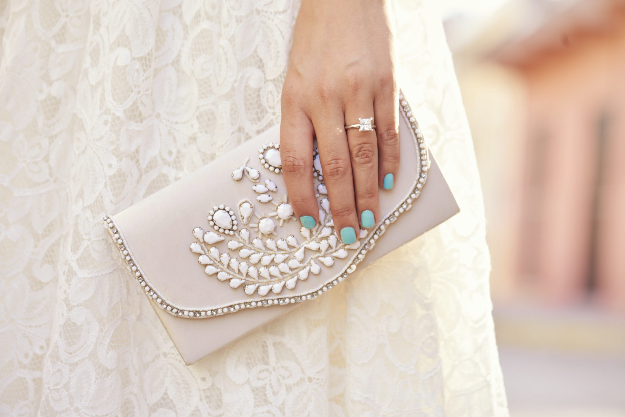 Hand with engagement ring holding beaded clutch