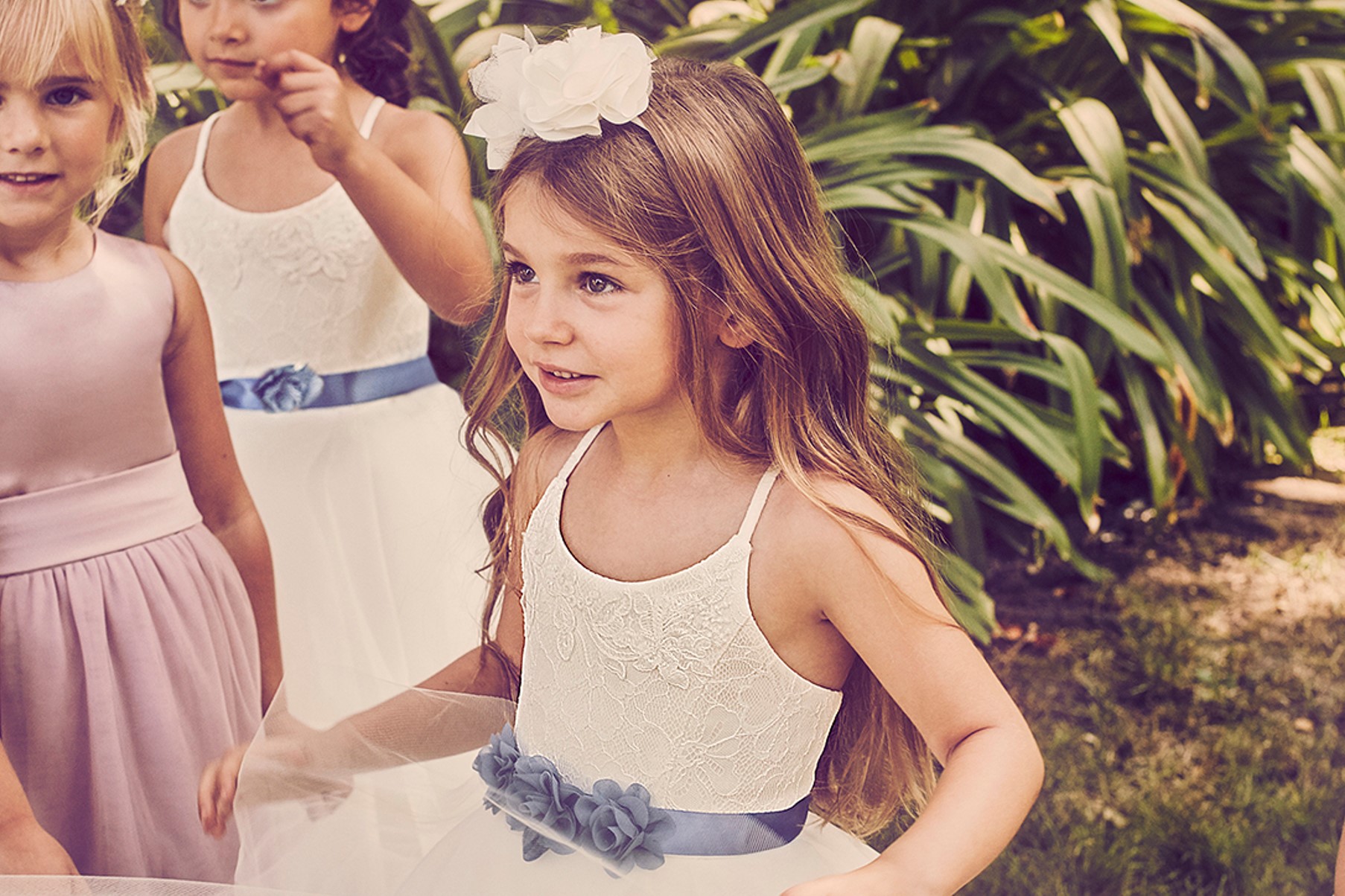 Flower girl in lace flower girl dress with blue floral sash
