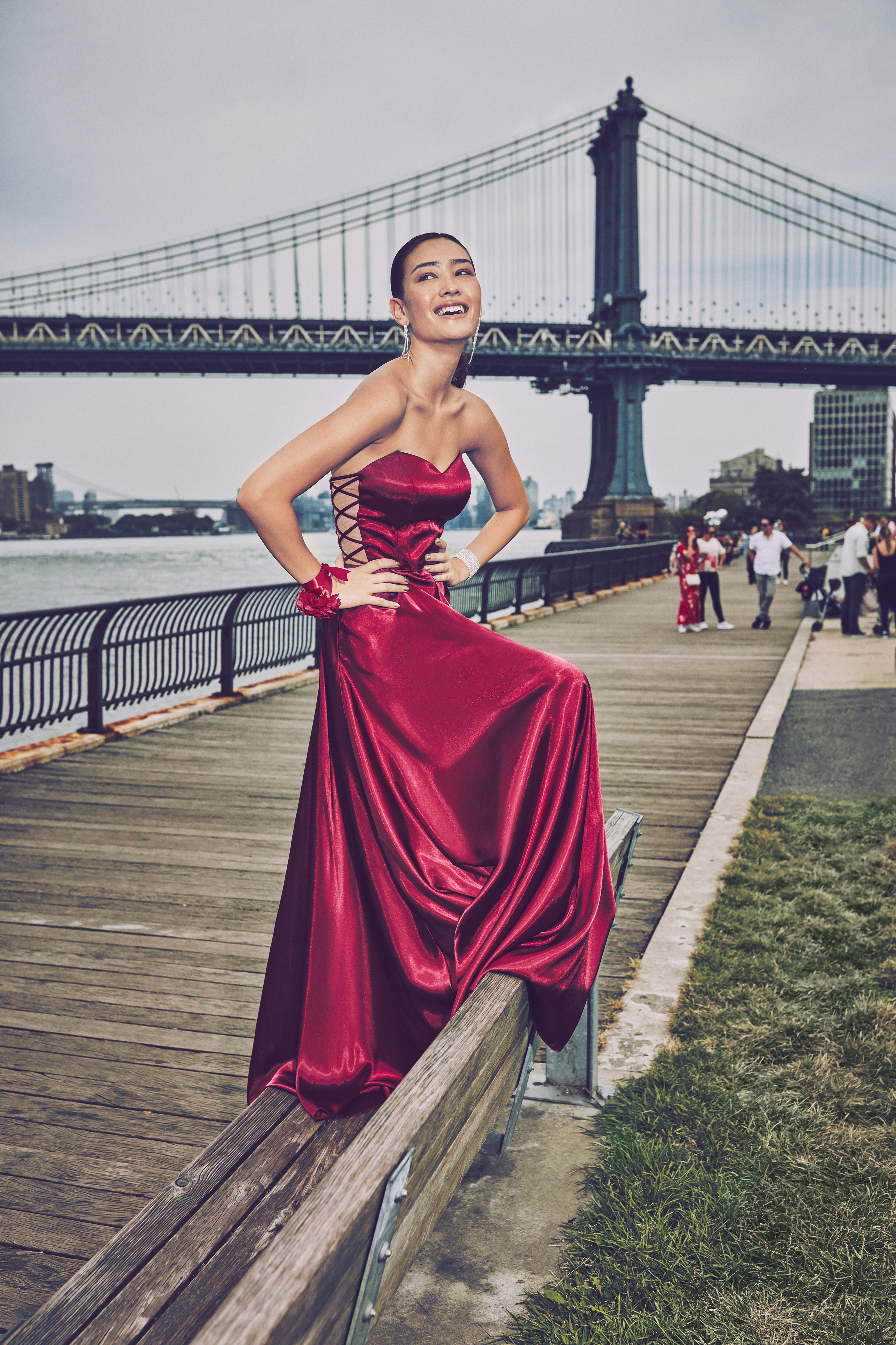 Girl in maroon strapless prom dress in front of the Brooklyn Bridge