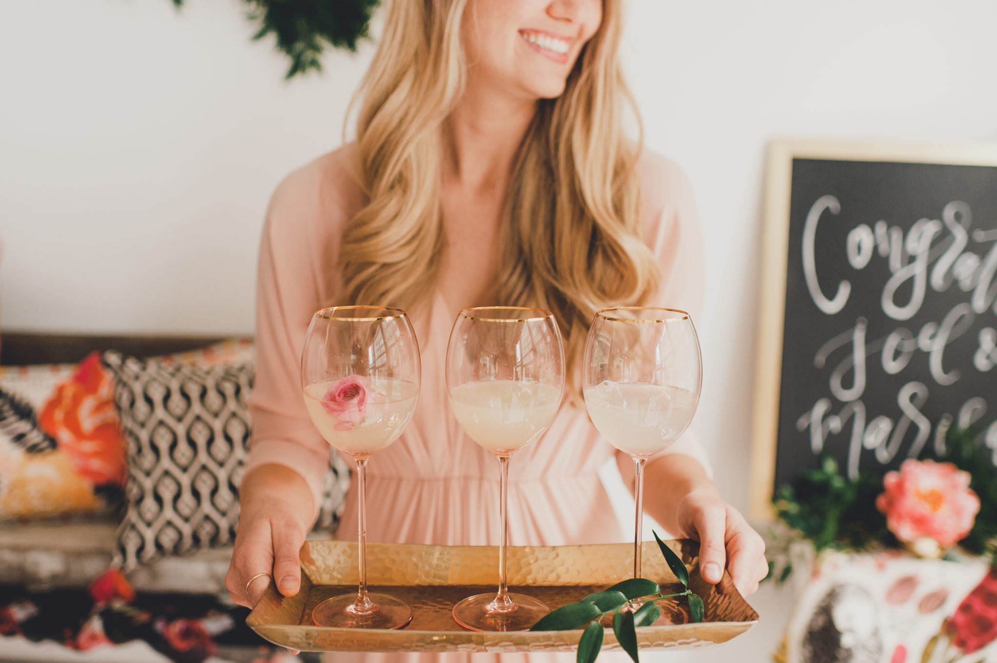 Blonde Woman holding tray of rose wine glasses.