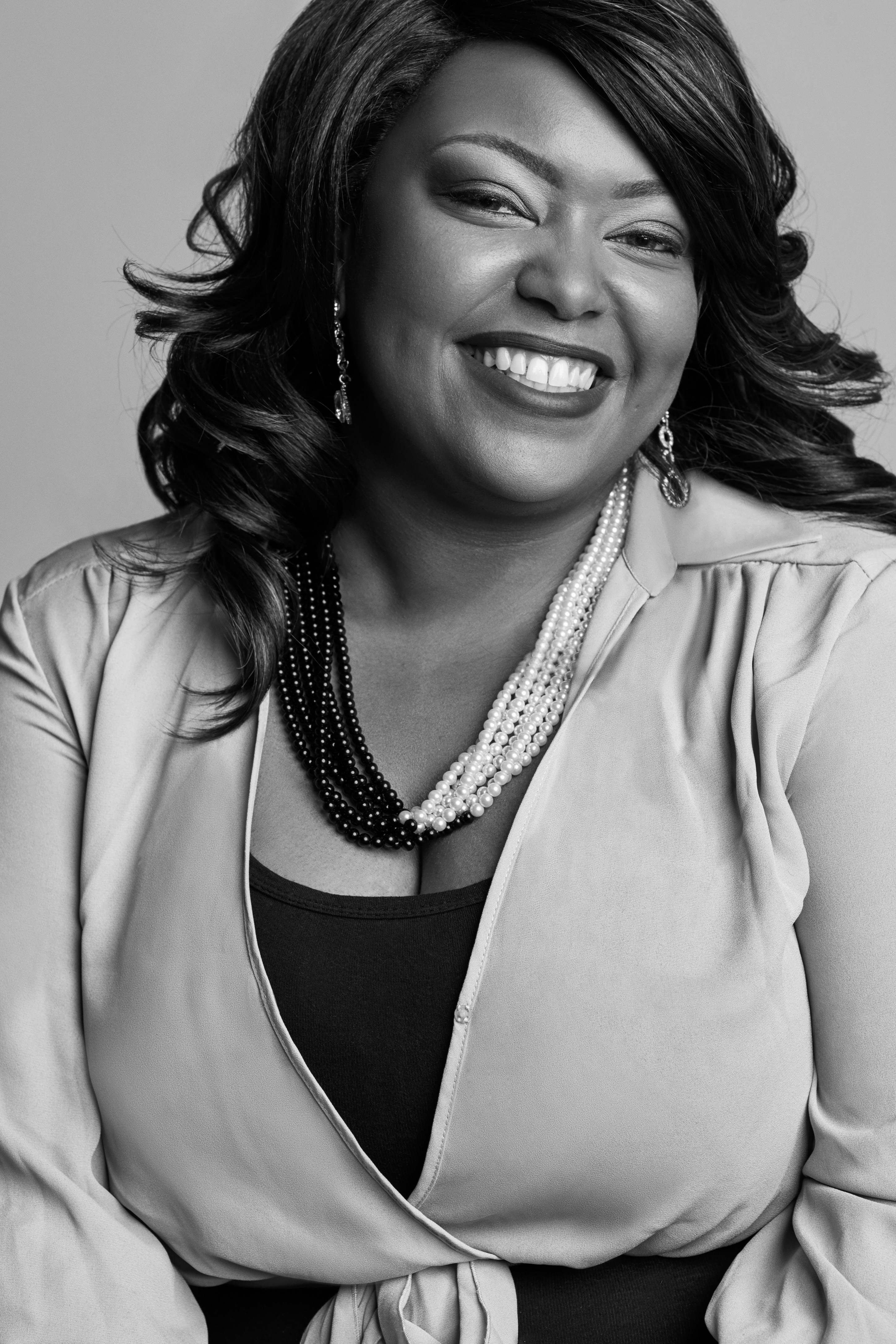 Shannon, David's Bridal's Manager of CRM Operations & Technology (African American woman in light colored silk blouse and black and white beaded necklace)