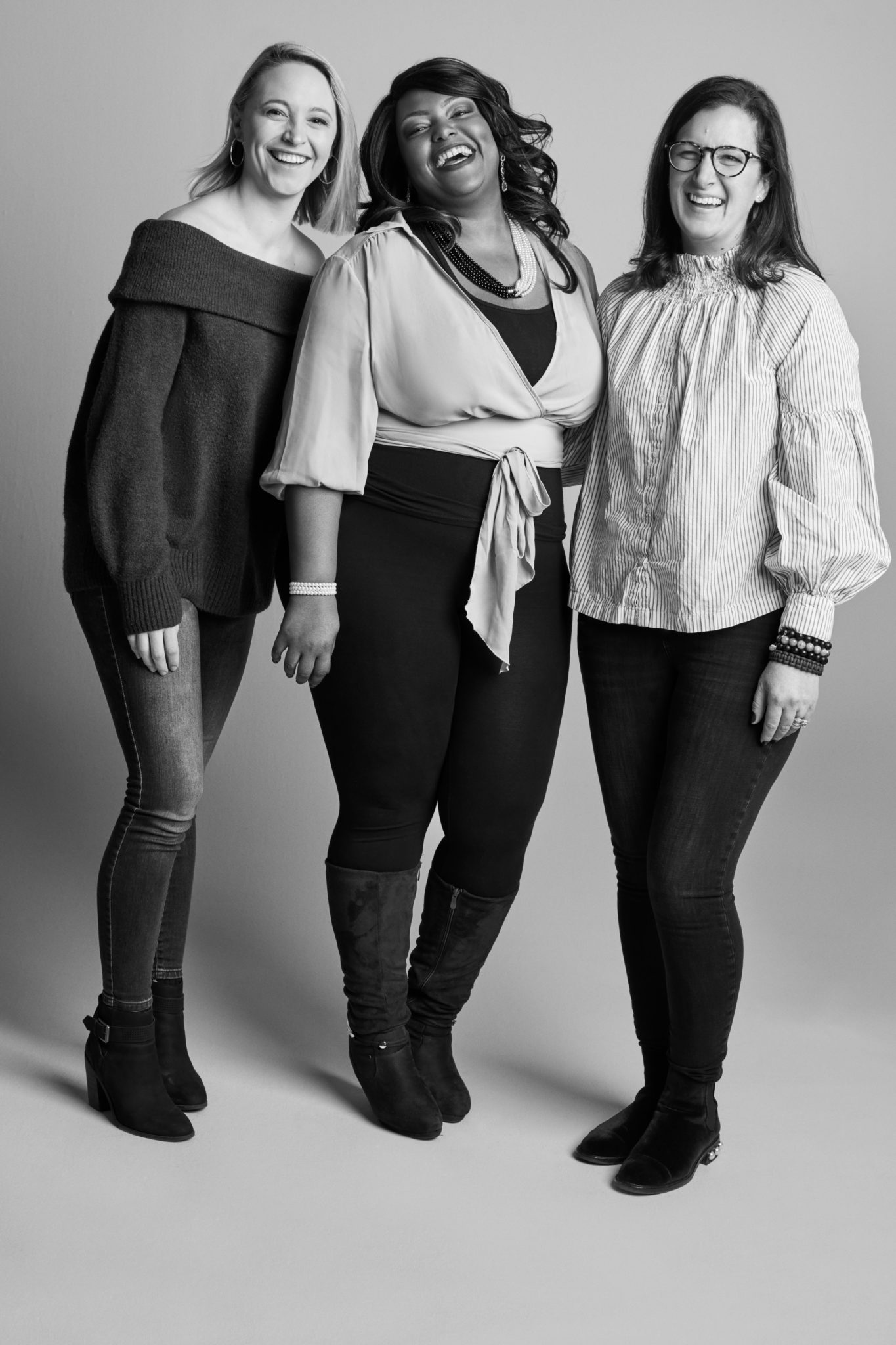 Three women from David's Bridal's Digital team smiling and pictured in a photo studio setting)
