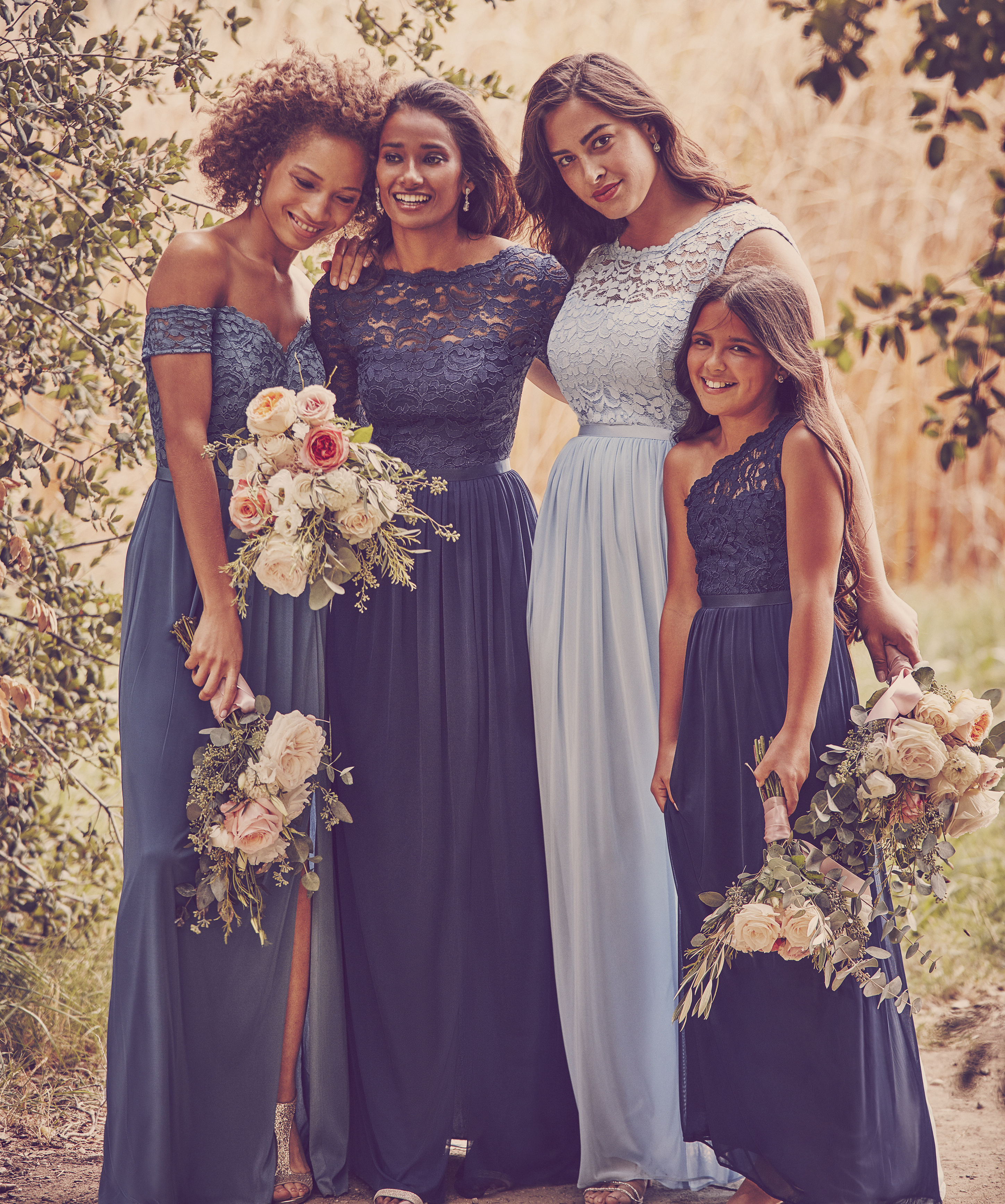 Women and child smiling in long lace bridesmaid dresses