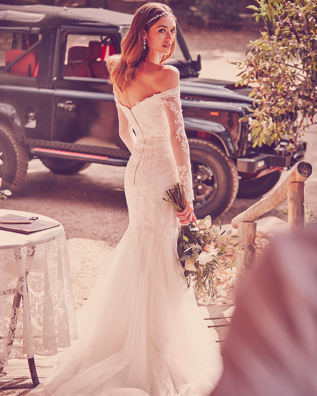 Bride from behind in a long sleeve off-the-shoulder trumpet wedding dress with lace details
