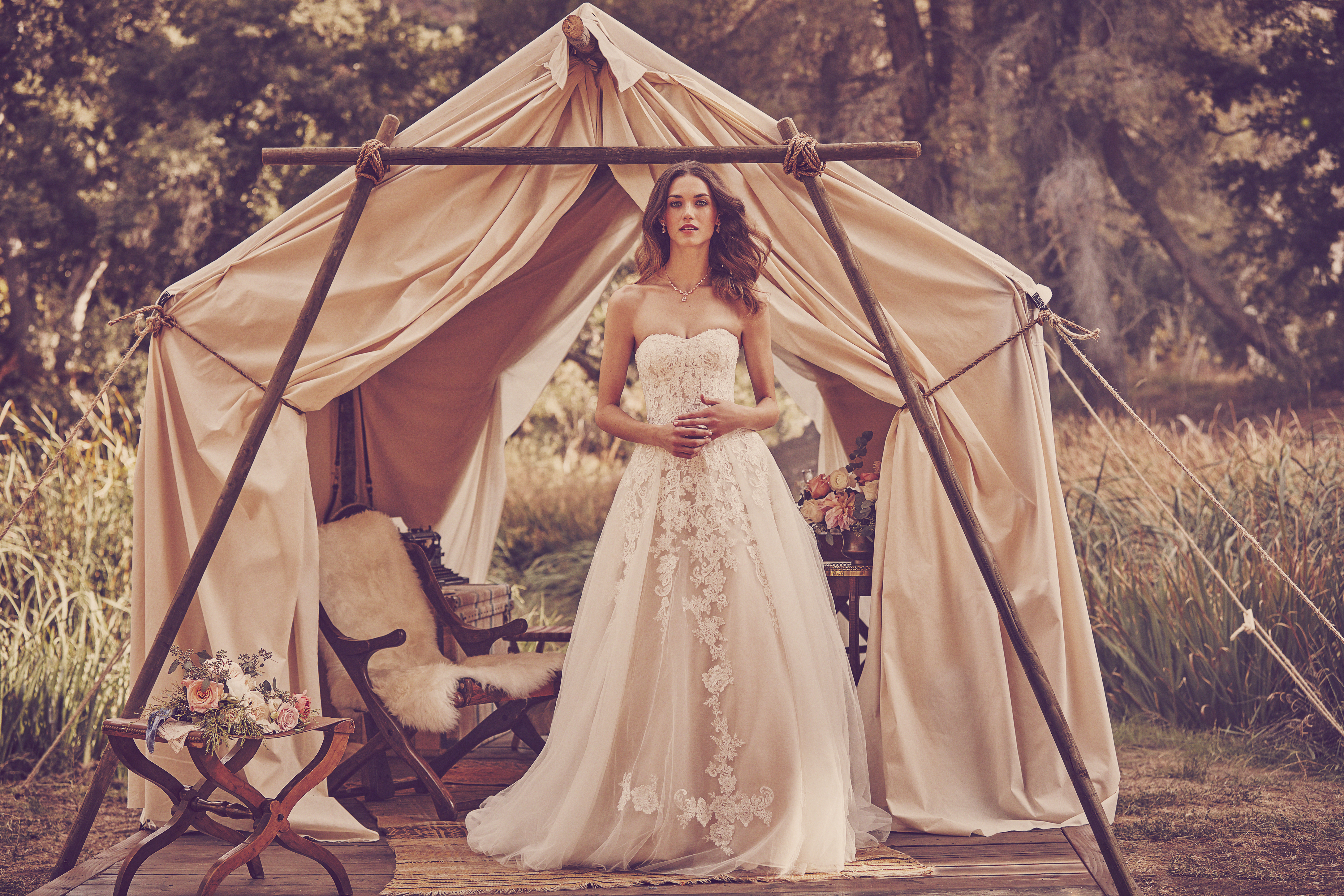 Woman standing in front of tent in ball gown wedding dress