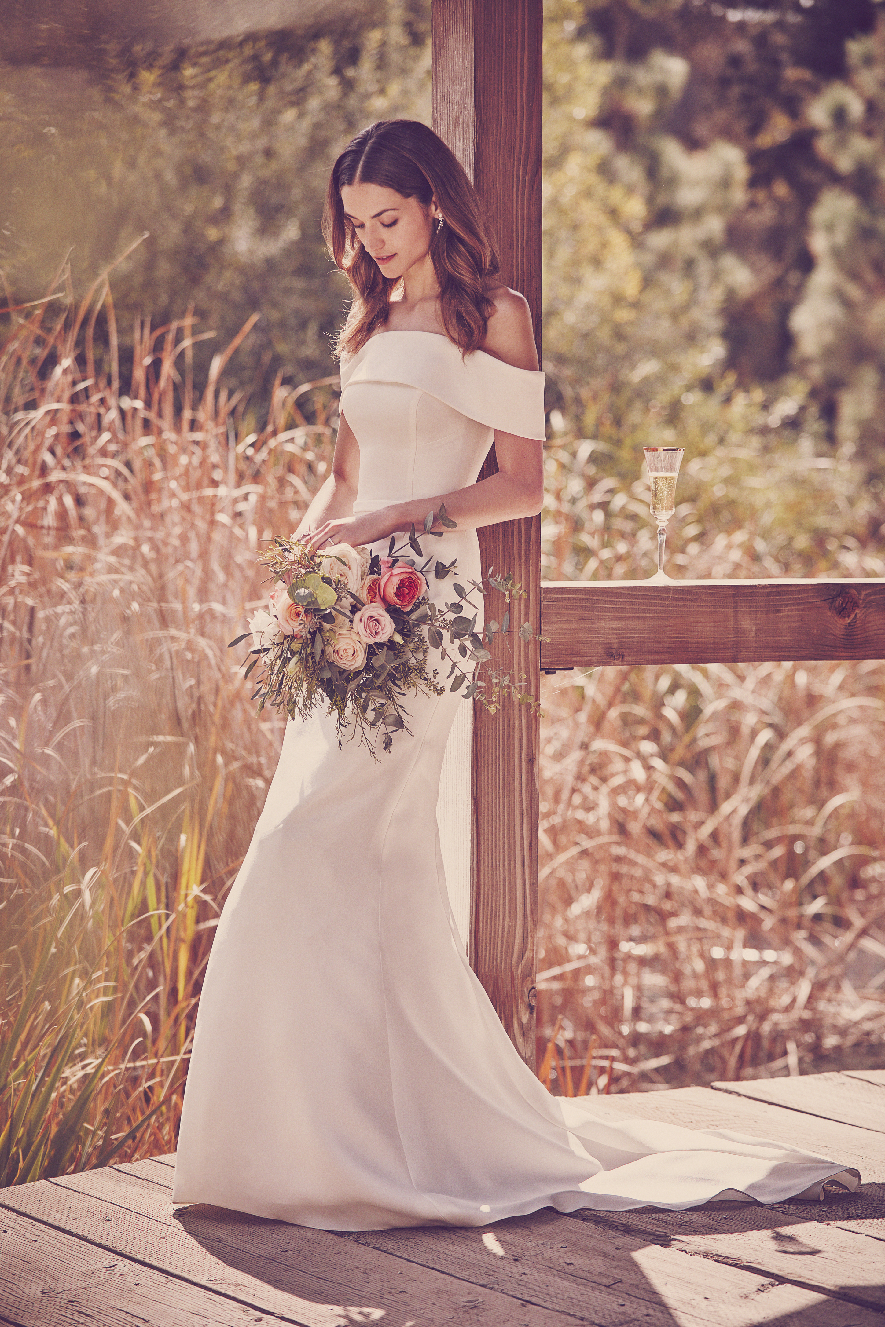 Woman on covered bridge leaning against post holding bouquet of flowers