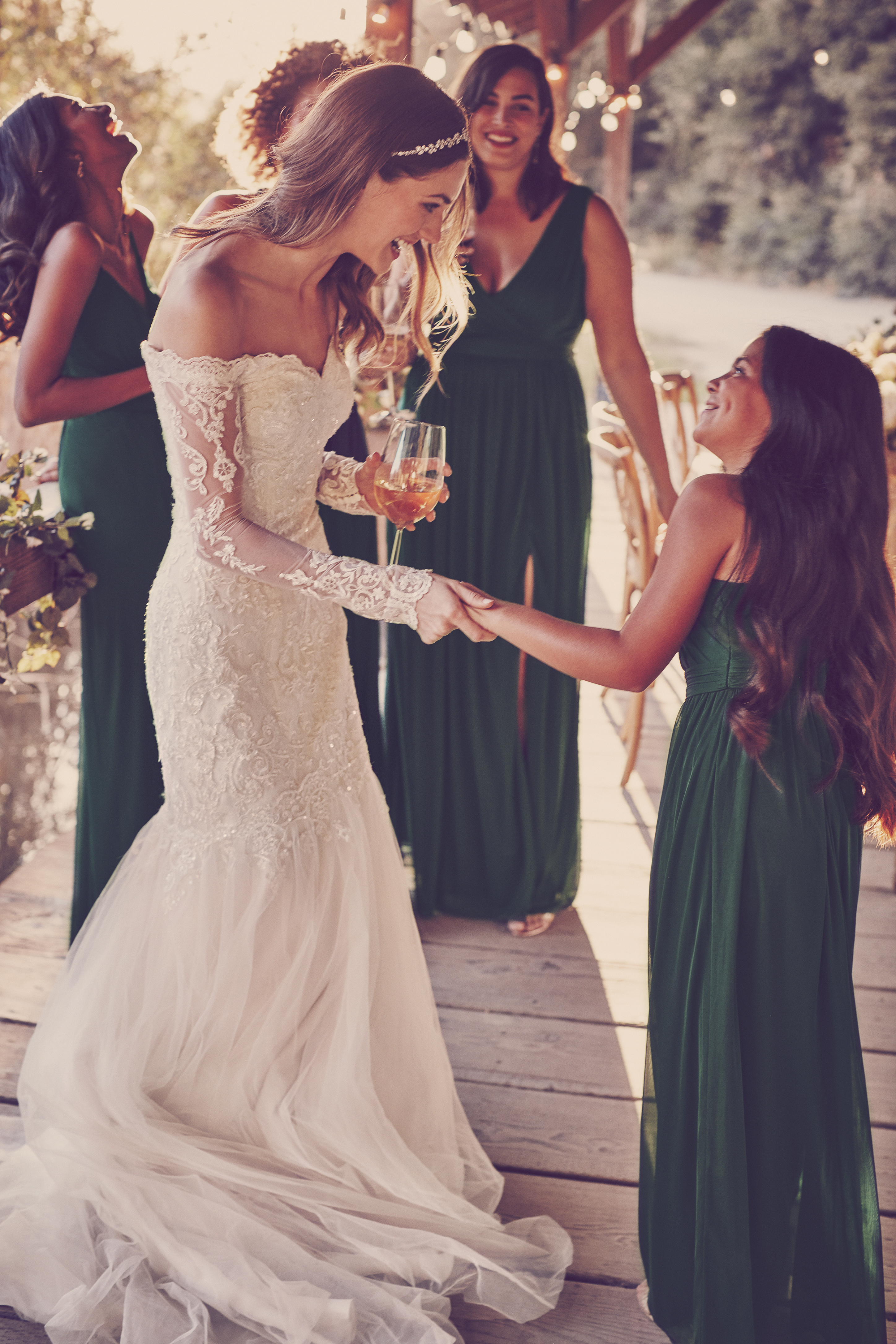 Woman and child smiling on covered bridge in formal wedding and bridesmaid dresses