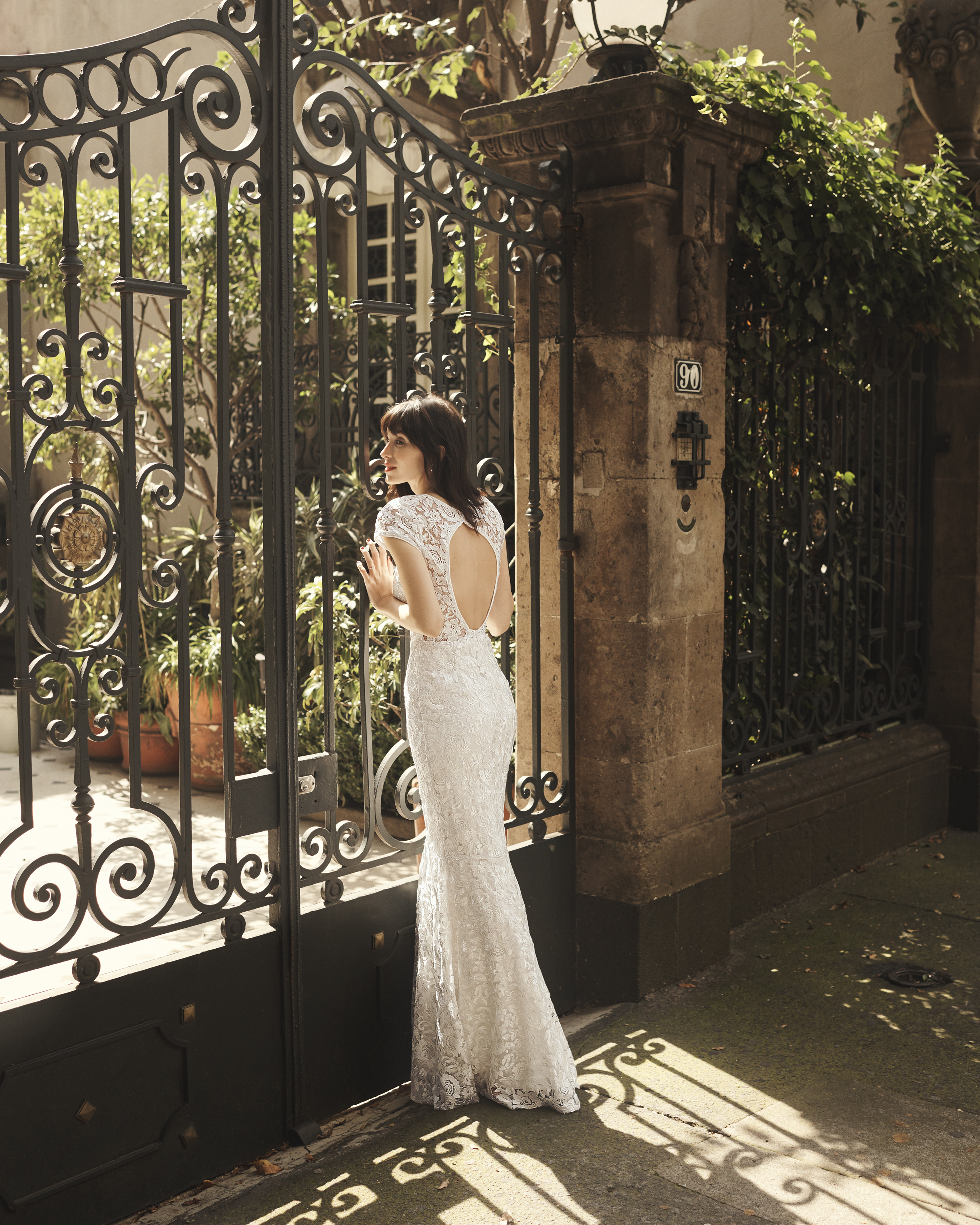 Bride standing in front of ornate gate in cutout long wedding dress