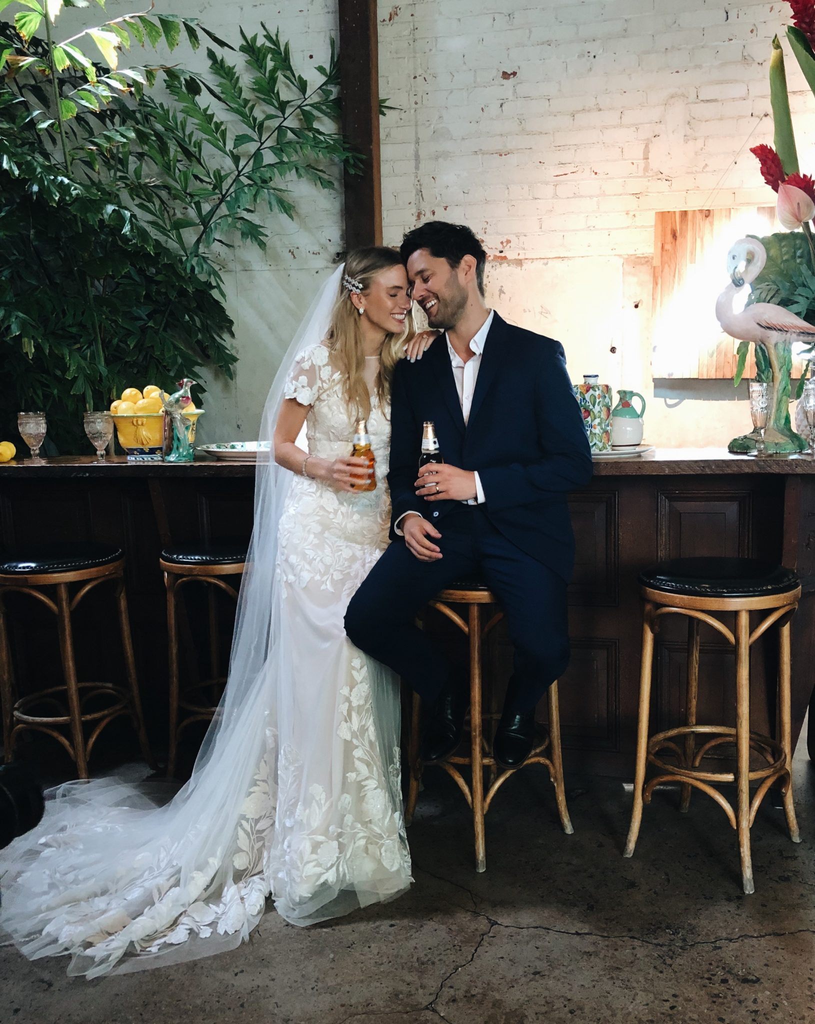 Bride and Groom smiling on wedding day holding beer bottles