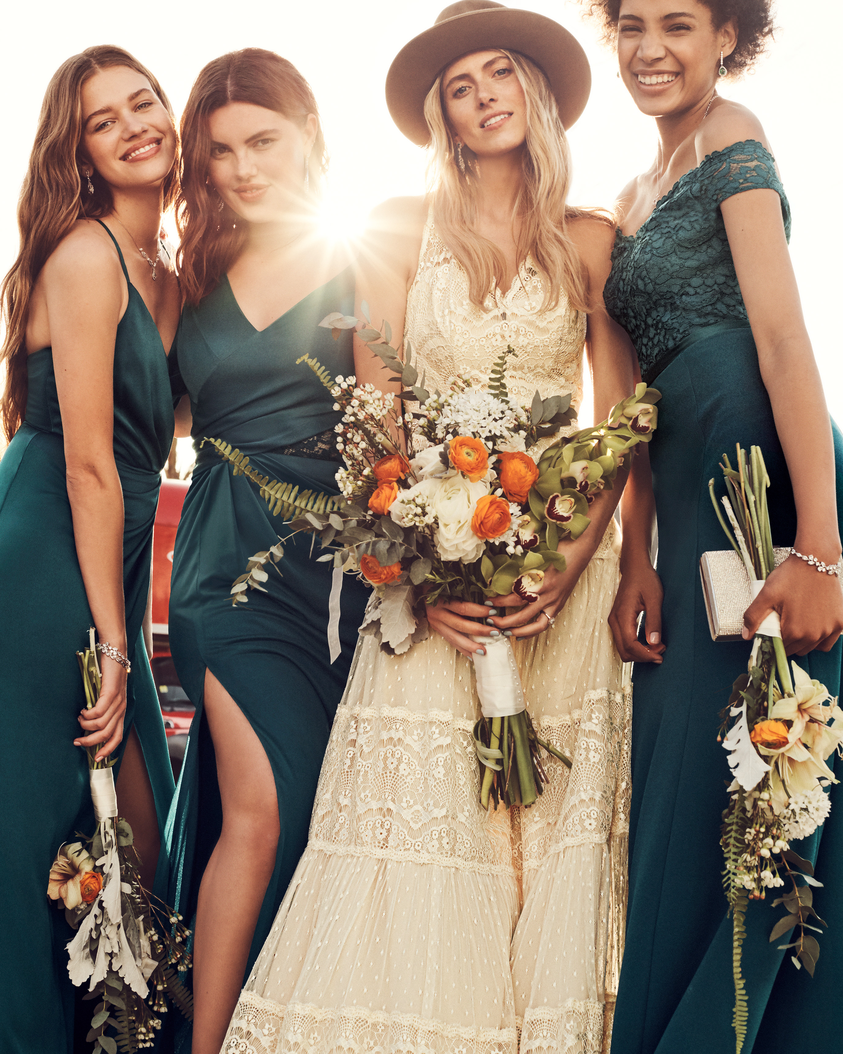 Bride and bridesmaids posing for camera in long dresses