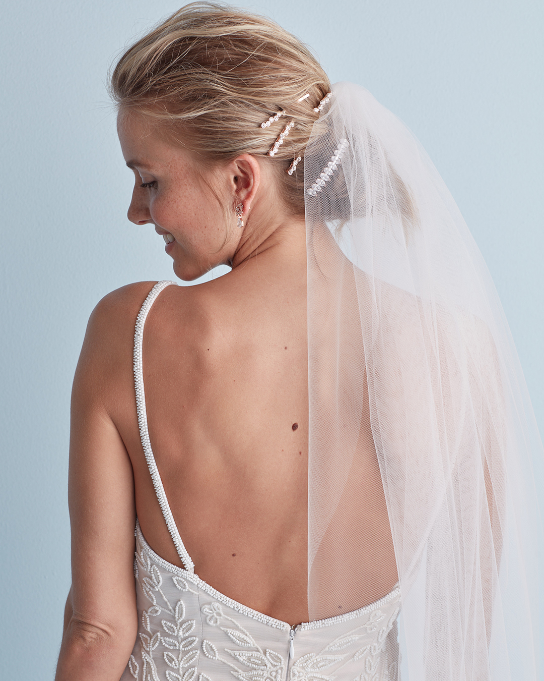 Wedding hairstyle with layered pins and veil in messy bun