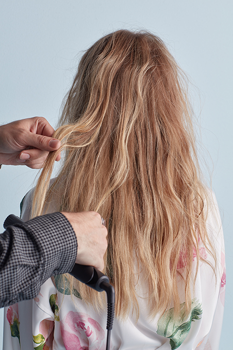 Hair stylist creating textured S waves with flat iron