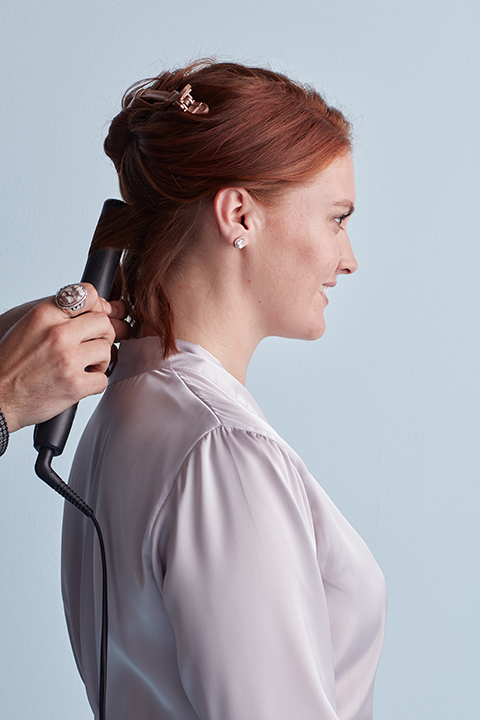 Hair stylist creating textured S waves with flat iron