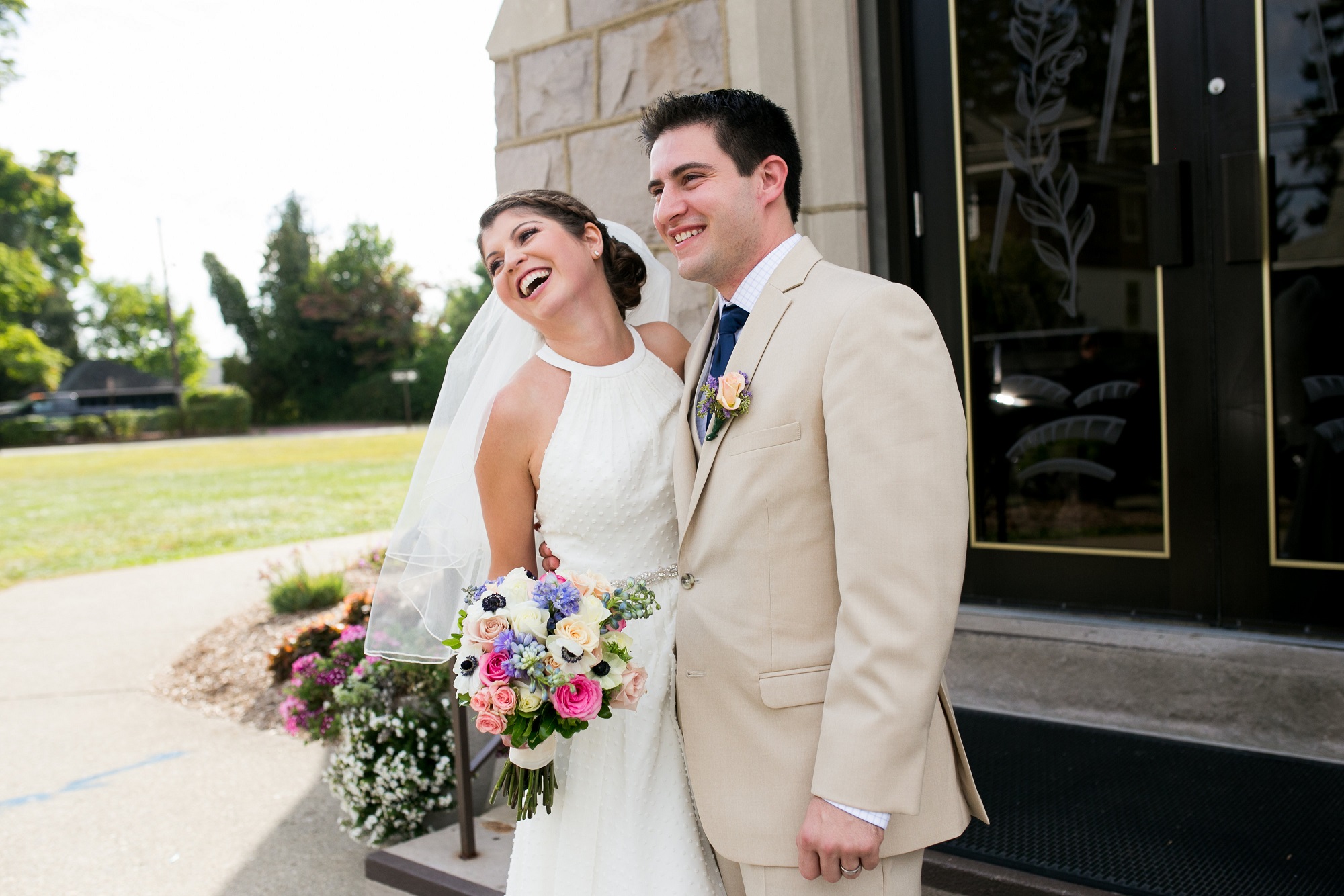 Bride and groom laughing outside church