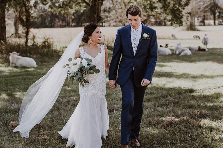 Bride with white bouquet and groom in a pasture