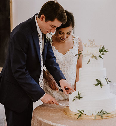 Bride and groom cutting a four-tier wedding cake. 