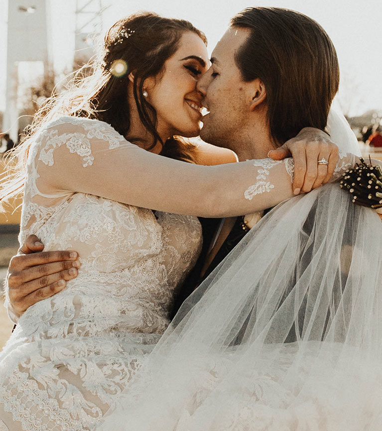 Bride and groom wrapped in veil kissing