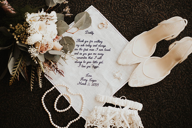 Bride's wedding details: bridal bouquet, handkerchief, pearl earrings and necklace, lace shoes and garter set. 