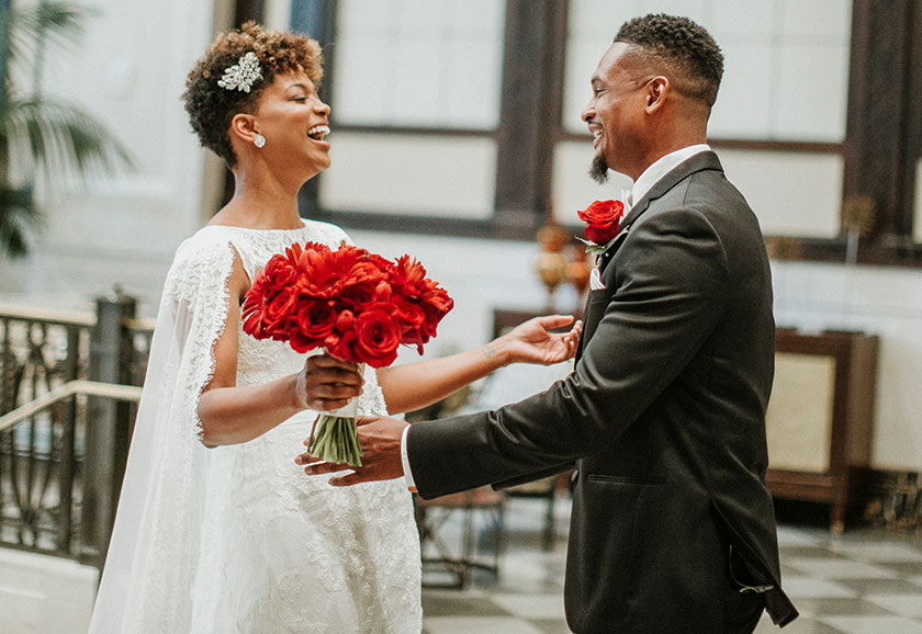 Bride Holding Red Bouquet Looking at Groom