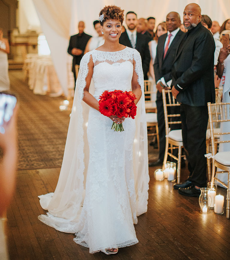 Bride  walking down the aisle with a red floral bouquet