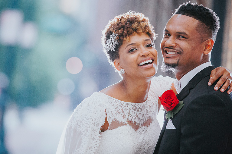 Bride and groom embracing and laughing facing the camera