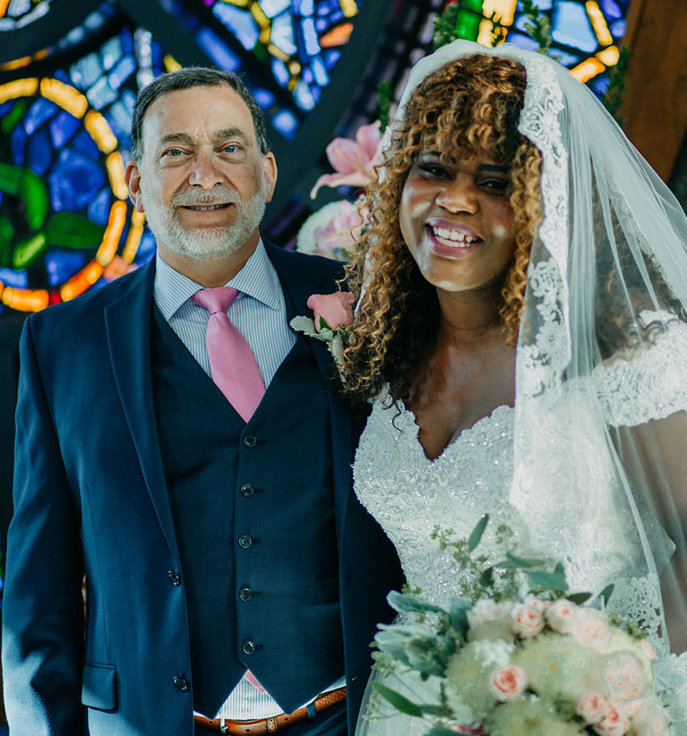 Bride and groom in front of stained glass window