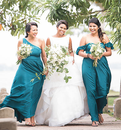 Bride walking with two bridesmaids in deep turquoise dresses