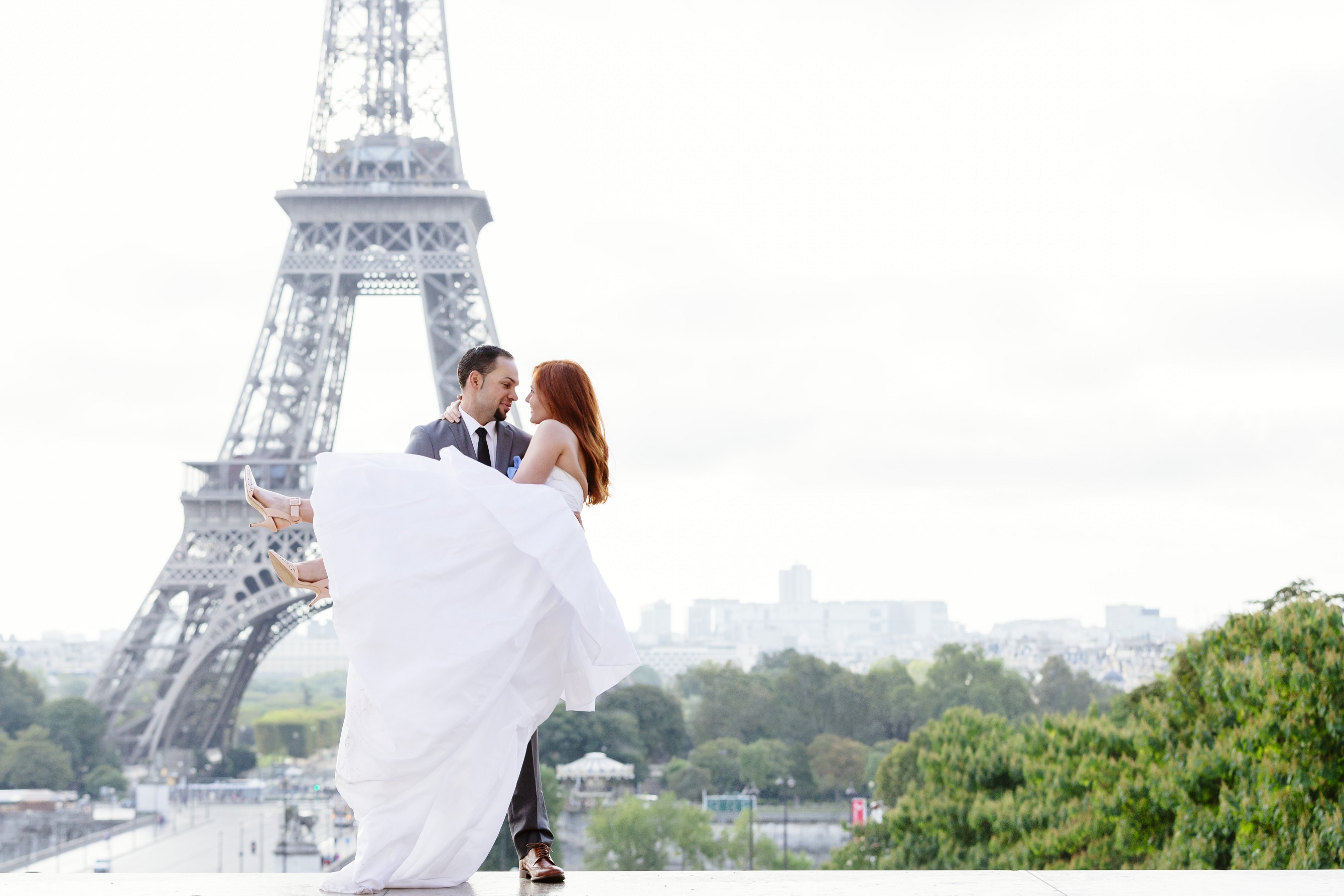 Groom TJ lifts up Bride Emily in front of the Eiffel Tower