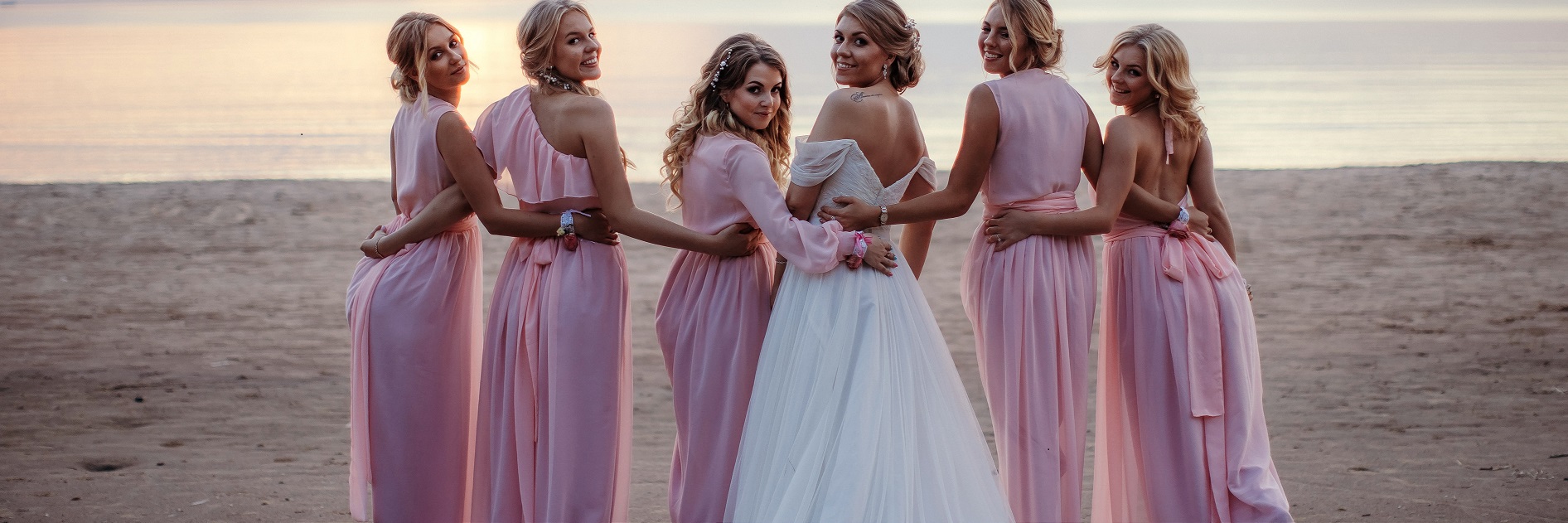 Bride Anna with her bridal party at the beach at sunset. 