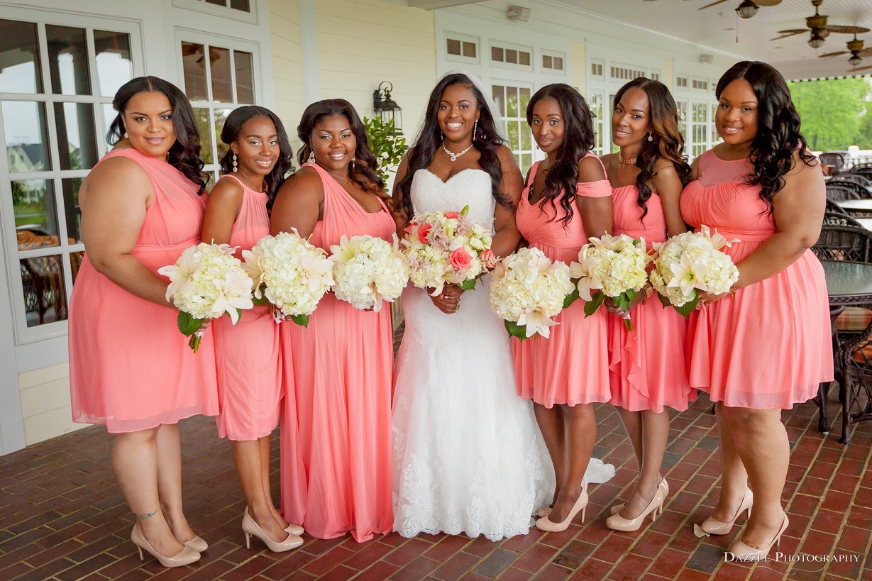 Bride with six bridesmaidsub coral  bridesmaid dresses, each holding a white bouquet. 