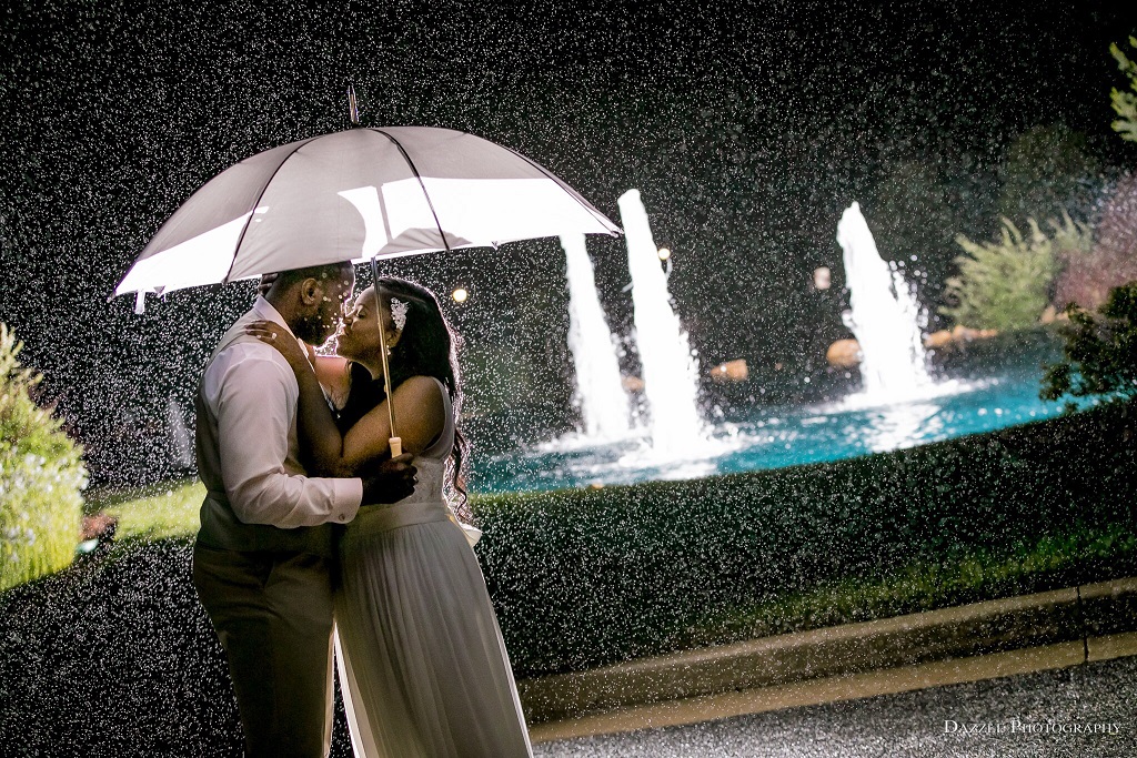 Bride and groom dancing under an umbrella in the rain