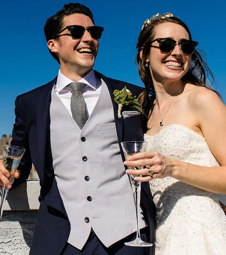 Bride and groom wearing sunglasses and drinking champagne