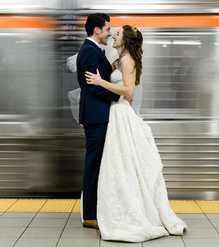 Bride and groom embracing with moving subway car behind them