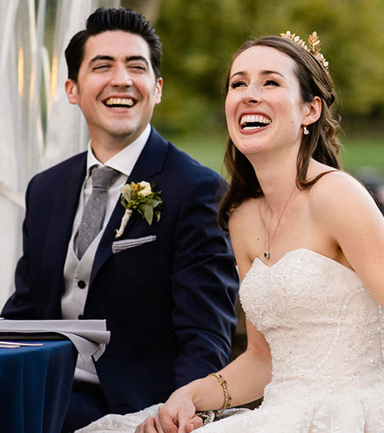 Bride and groom laughing while seated at a table during the wedding reception