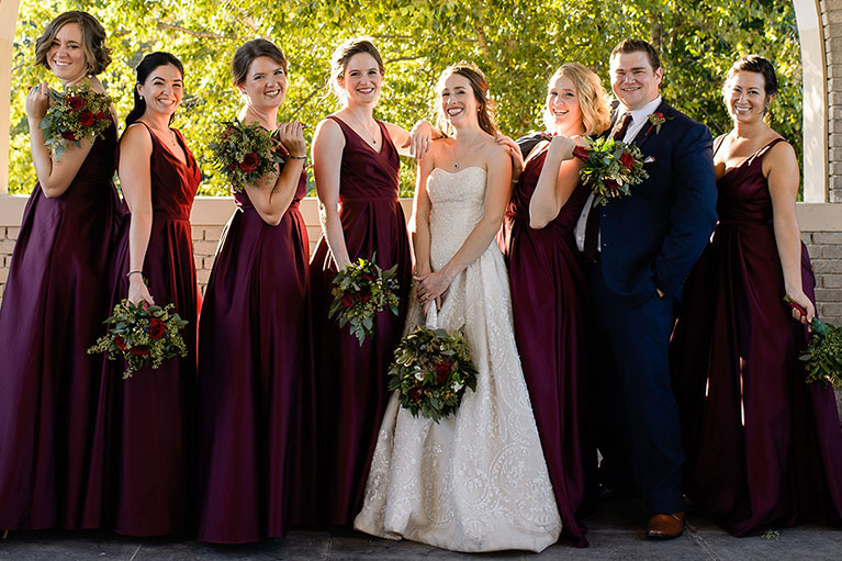 Bride with 6 bridesmaids in wine colored dresses and 1 bridesman in a navy blue suit