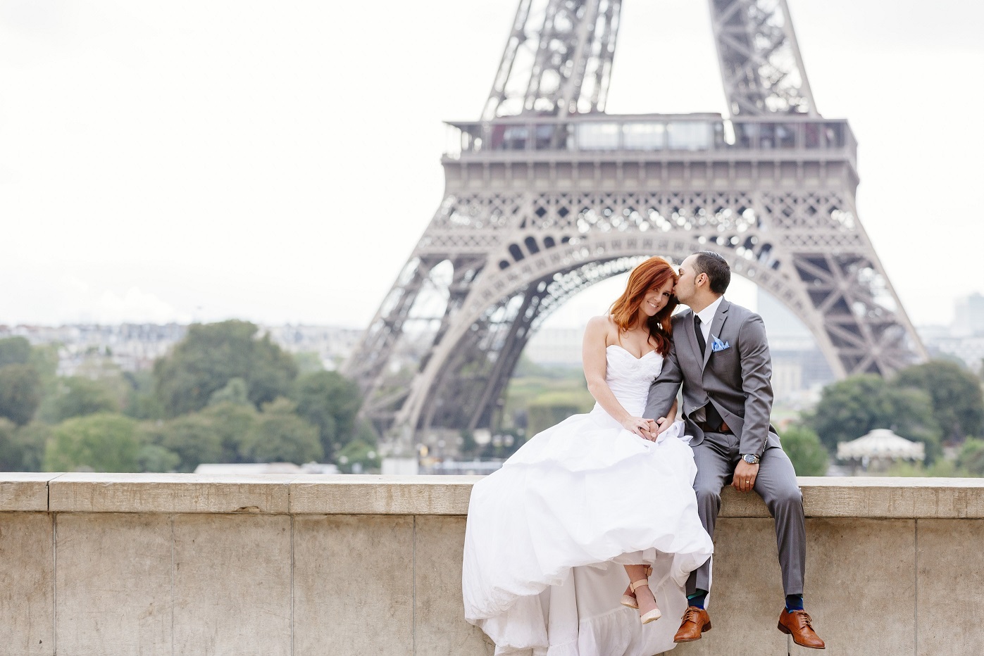 Real Bride Emily and TJ sit in front of the Eiffel Tower. 