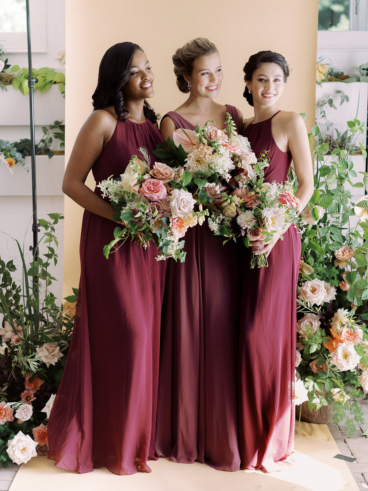 Bridesmaids posing for a group photo wearing David's Bridal gowns in the colors Wine and Chianti for the fall season.