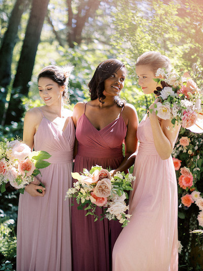 Group of bridesmaids wearing different shades of pink posing for a photo