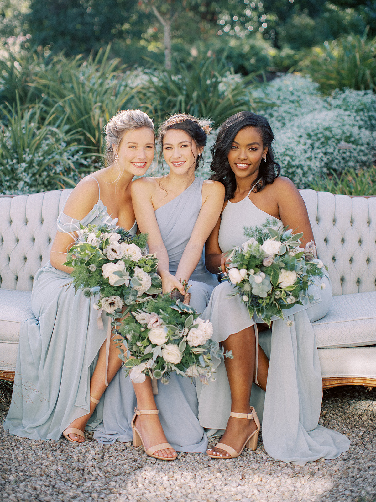 Group of bridesmaids sitting down and posing for a photo wearing dresses in the color Dusty Blue for the Winter season.