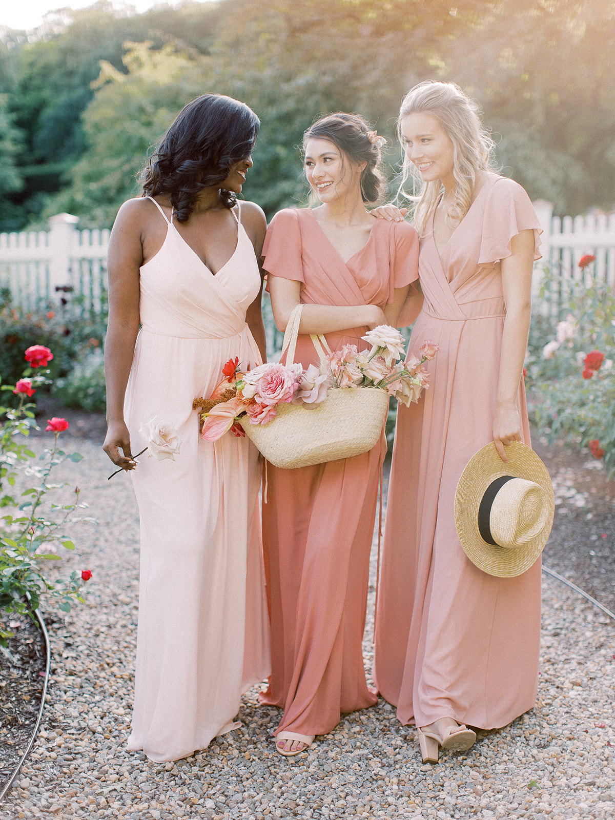 Bridesmaids posing for a group photo wearing David's Bridal gowns in the colors Petal, Sedona, and Ballet for the Summer season.