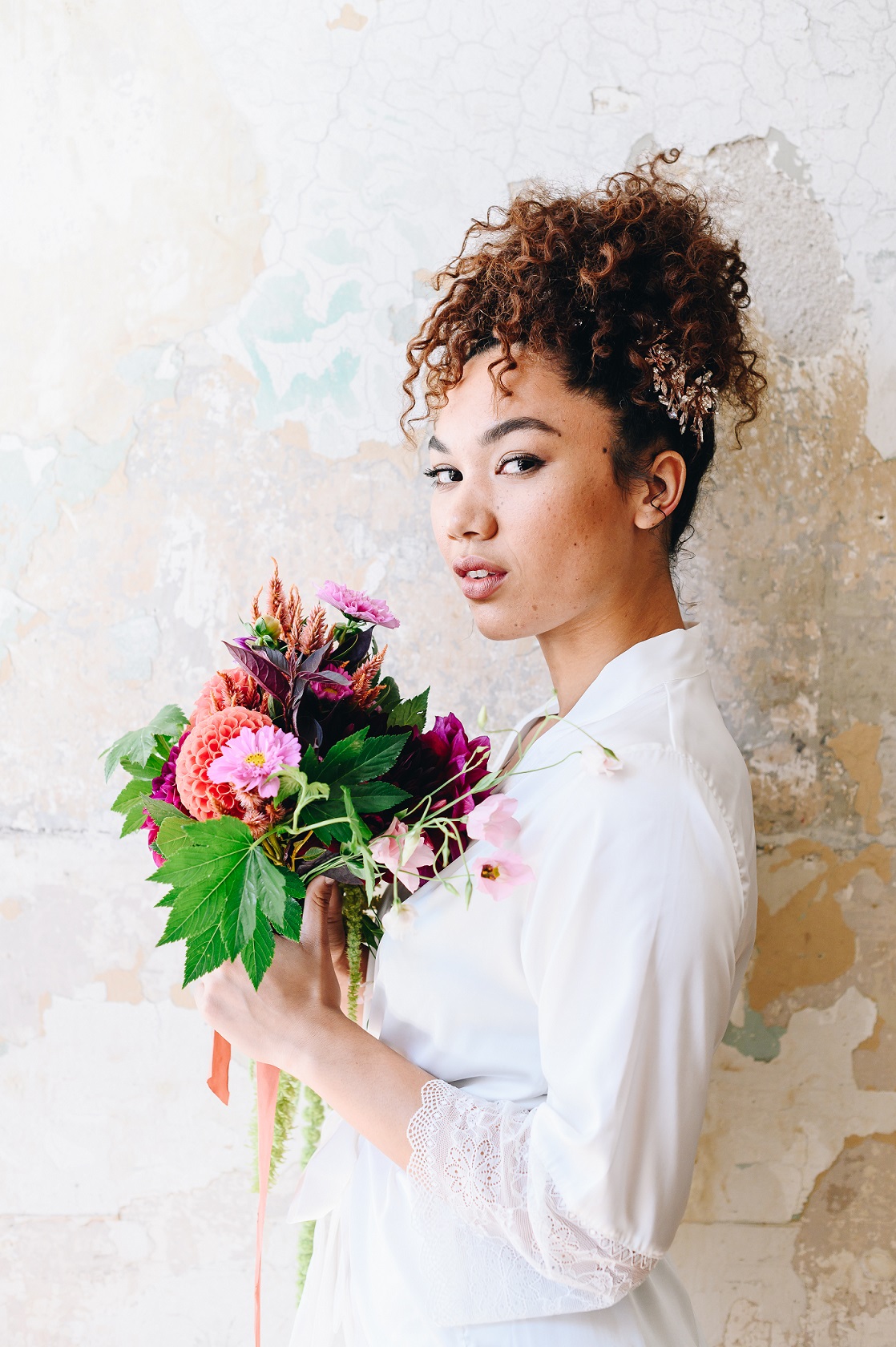 Bride holding bouquet with curly wedding hairstyle