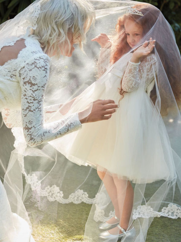 bride playing with flower girl in matching dresses