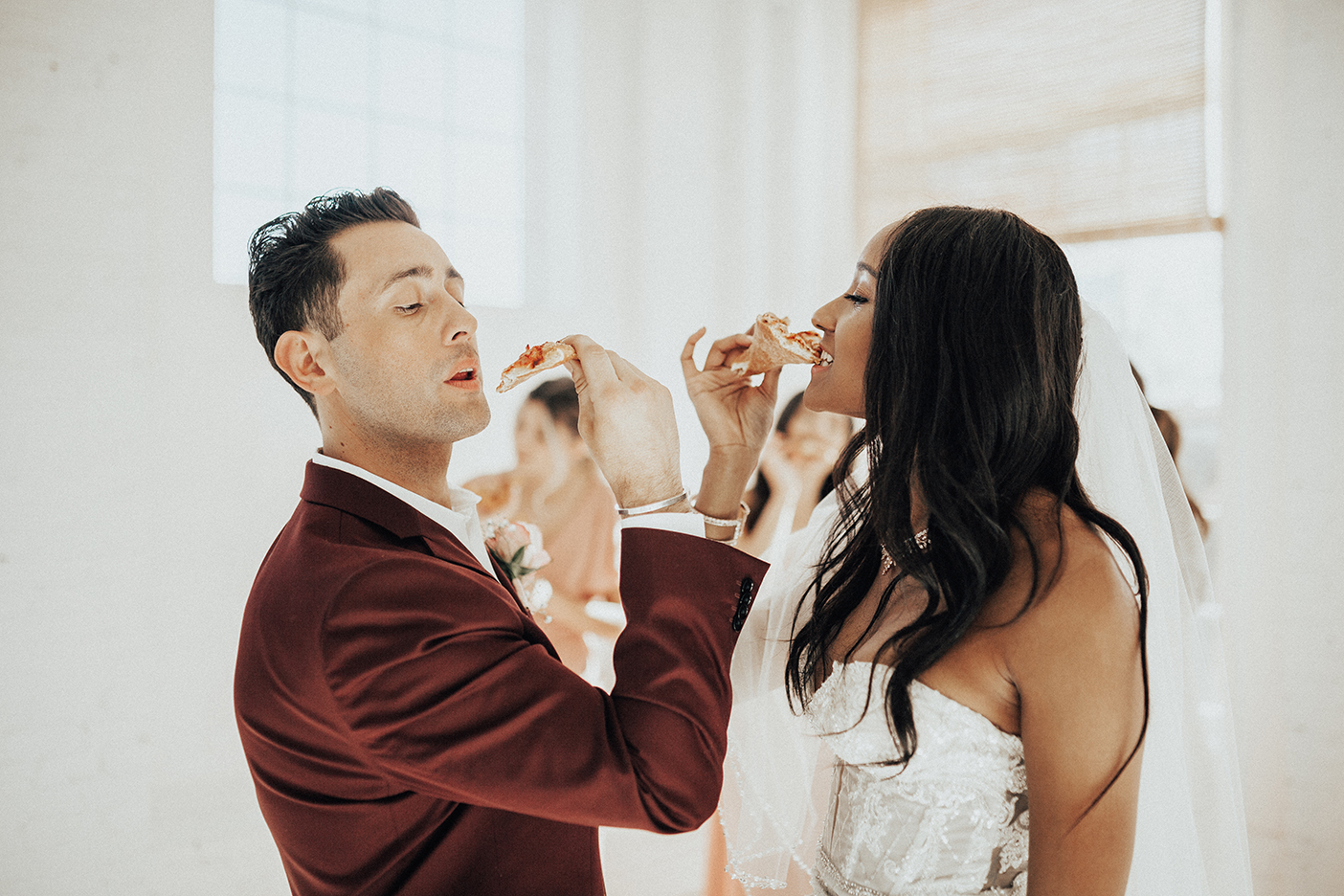 Bride and groom enjoying a slice of pizza at their reception.
