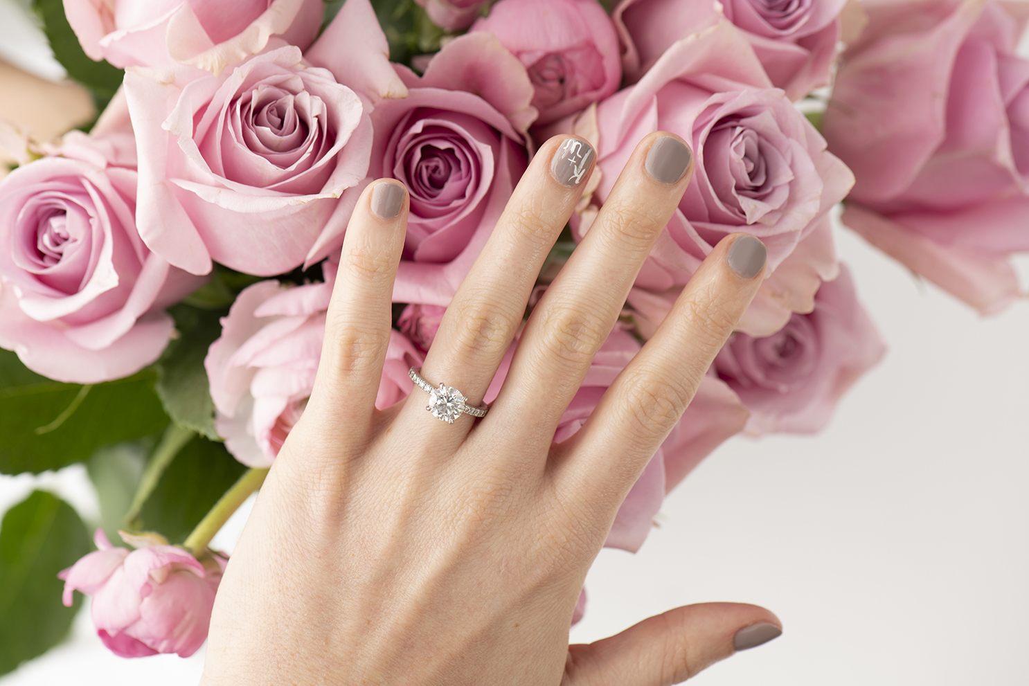 A woman's hand in front of pink roses.