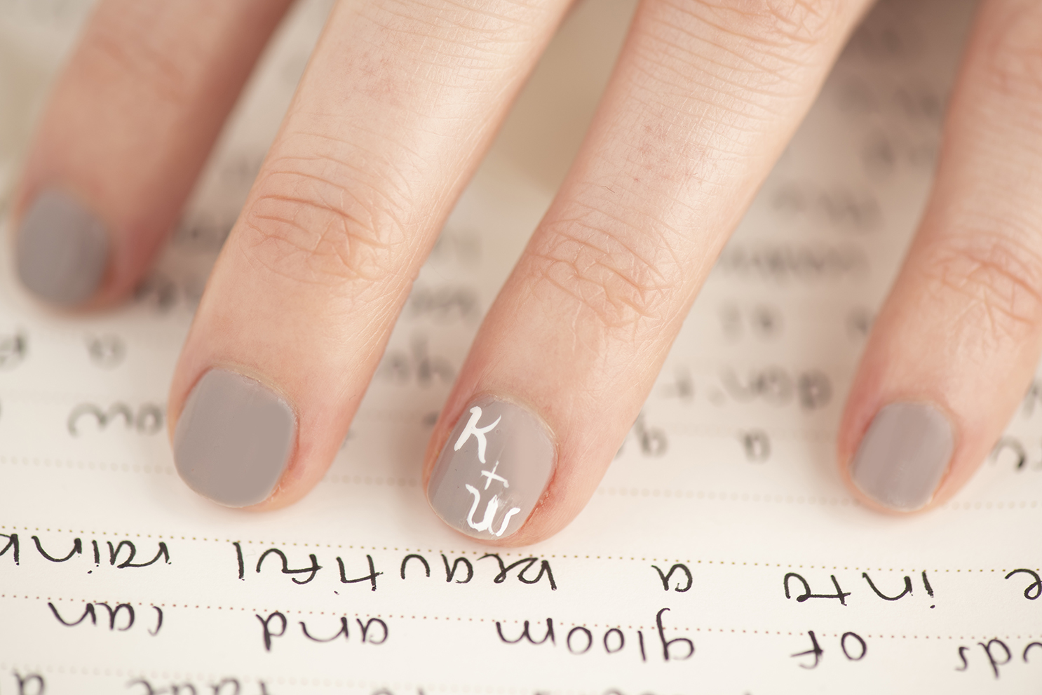 A close up of nail art on a woman's hand, hovering over her vows.