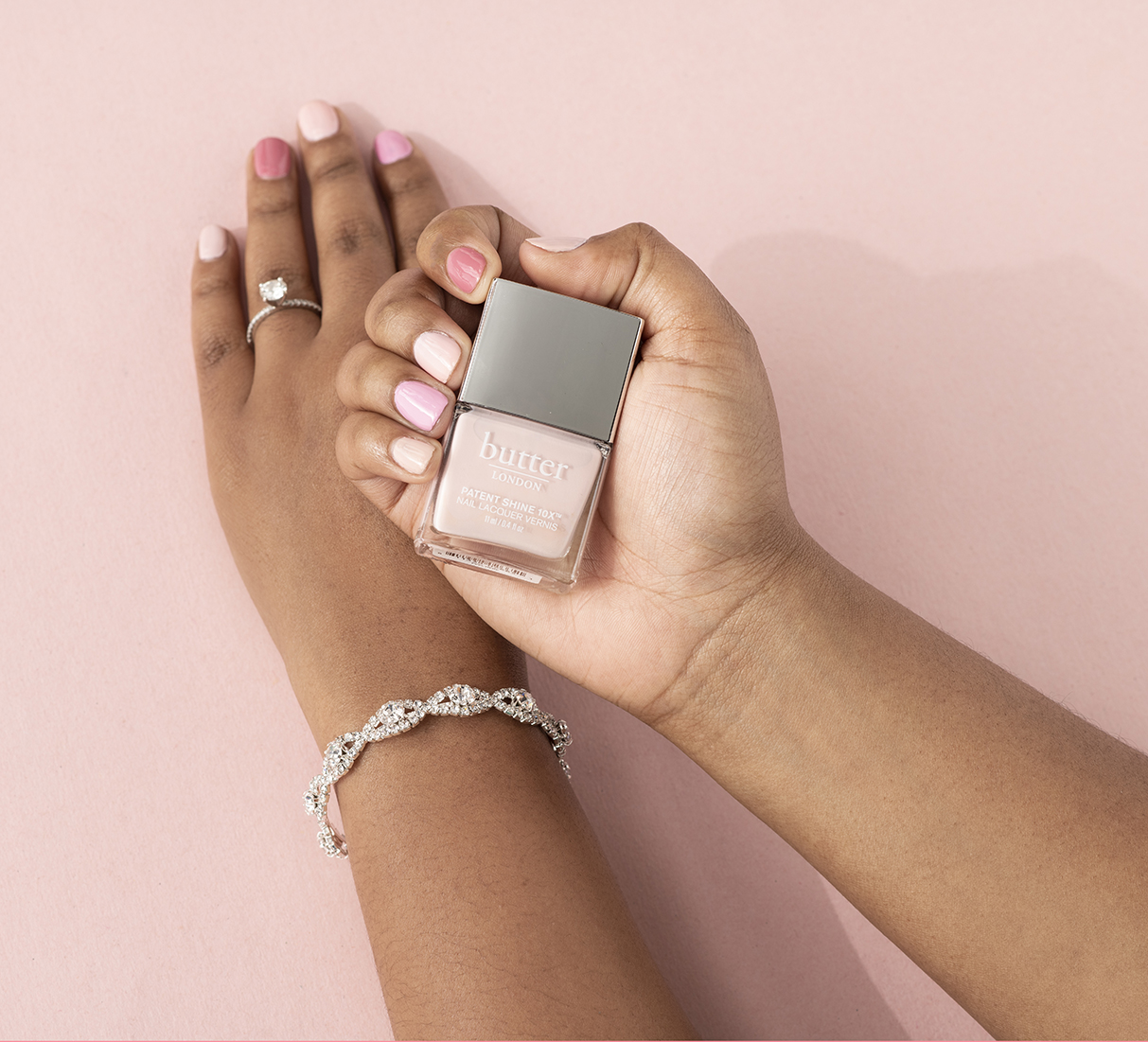 Woman with a multicolor manicure holding a nail polish bottle.